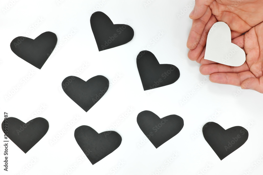 World humanitarian day, be kind, spread pure love, charity and kindness concept. Hands holding white heart among black ones.