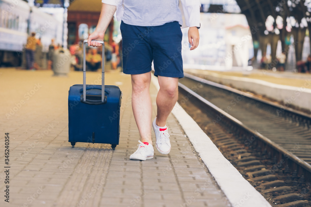 man with suitcase on wheels walking by railway station platform man with suitcase on wheels walking by railway station platform