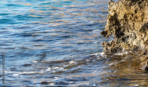 Sea wave on the stones, foamy spray, summer landscape.