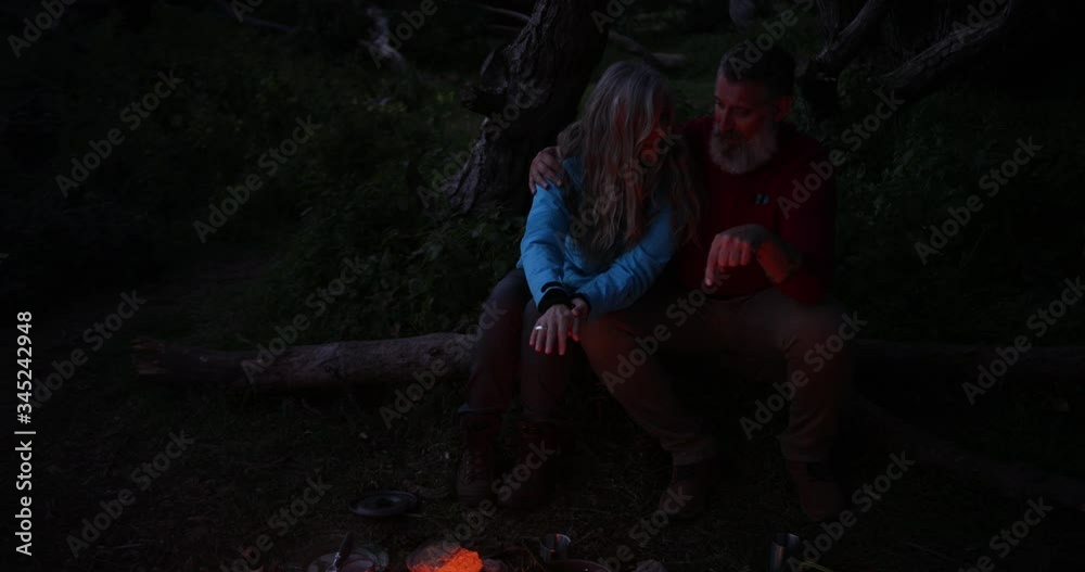 Senior couple sitting together and talking by the bonfire Senior couple sitting together and talking by the bonfire