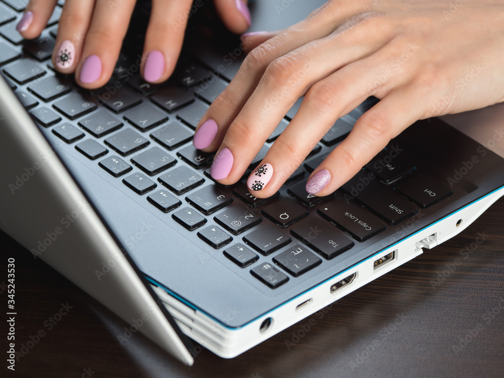 Close-up of typing woman hands with a creative manicure on the theme of coronavirus Close-up of typing woman hands with a creative manicure on the theme of coronavirus