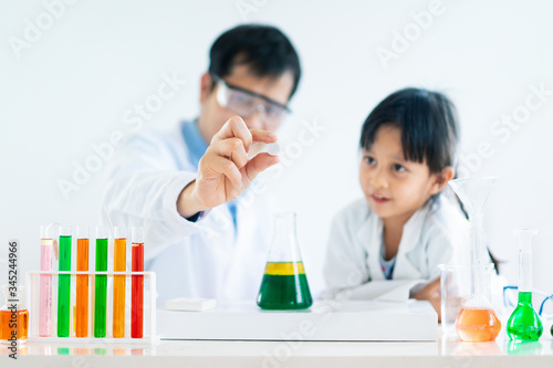 Asian father and little daughter make an experiment about phase separation of oil and water and how the effect of carbon dioxide in effervescent tablet reaction in the liquid, concept of homeschooling