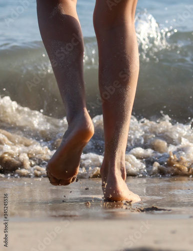 Feet of a girl walking on the seashore. © schankz