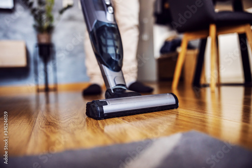 Fototapeta Naklejka Na Ścianę i Meble -  Close up of man using steam cleaner for parquet. Selective focus on cleaner. Home interior.