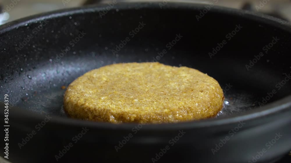 Chef preparing the burger, frying the meat with melted cheese on the pan. Frying cheeseburger meat on iron plate. Close up. Juicy delicious meat cutlets in a frying Pan are Fried On the Stove in oil. Chef preparing the burger, frying the meat with melted cheese on the pan. Frying cheeseburger meat on iron plate. Close up. Juicy delicious meat cutlets in a frying Pan are Fried On the Stove in oil.