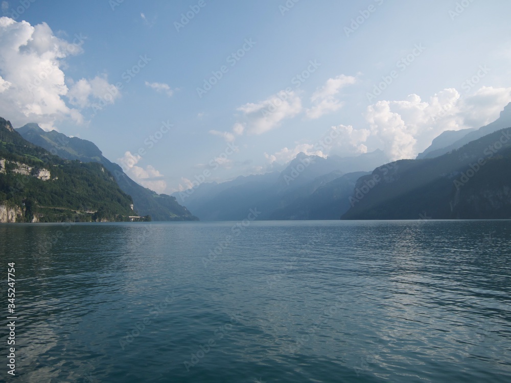 Vistas a un hermoso gran lago azul que reflejaba en el agua la cima de las montañas alpinas verdes que arañaban el cielo limpio azul a la luz de la puesta de sol
