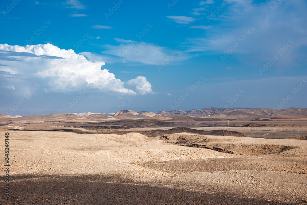 Beautiful dry landscape with colorful sand and cloudy blue sky. Dramatic view of the wilderness. The arid landscape of the prairie. Israel Negev Desert Sede Boker. Great view of the Nakhal Tsin rift. 