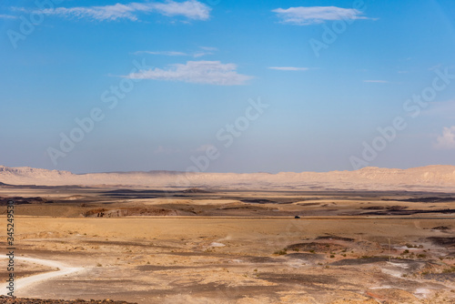 Beautiful dry landscape with colorful sand and cloudy blue sky. Dramatic view of the wilderness. The arid landscape of the prairie. Israel Negev Desert Sede Boker. Great view of the Nakhal Tsin rift. 