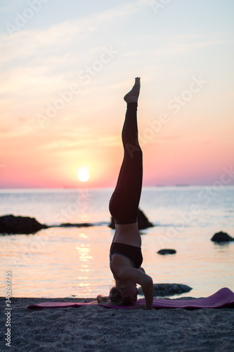 girl has a yoga practice on the beach among big stones. rocks in the sea. sunrise time