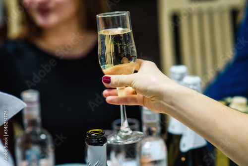 women's hand holding a glass of champagne at a festive party