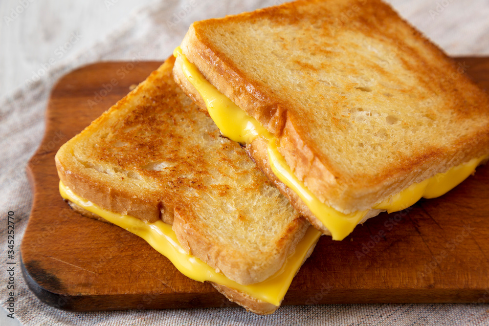 Homemade Grilled Cheese Sandwich on a rustic wooden board, side view. Close-up. Homemade Grilled Cheese Sandwich on a rustic wooden board, side view. Close-up.