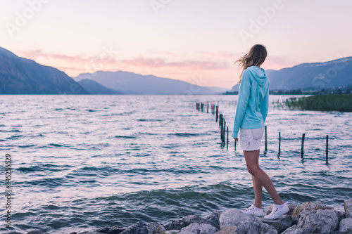 Femme en pull bleu regarde le coucher de soleil sur le lac 