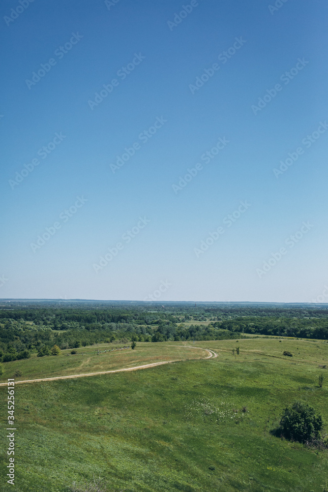 Fototapeta premium field road on a green hill and blue sky
