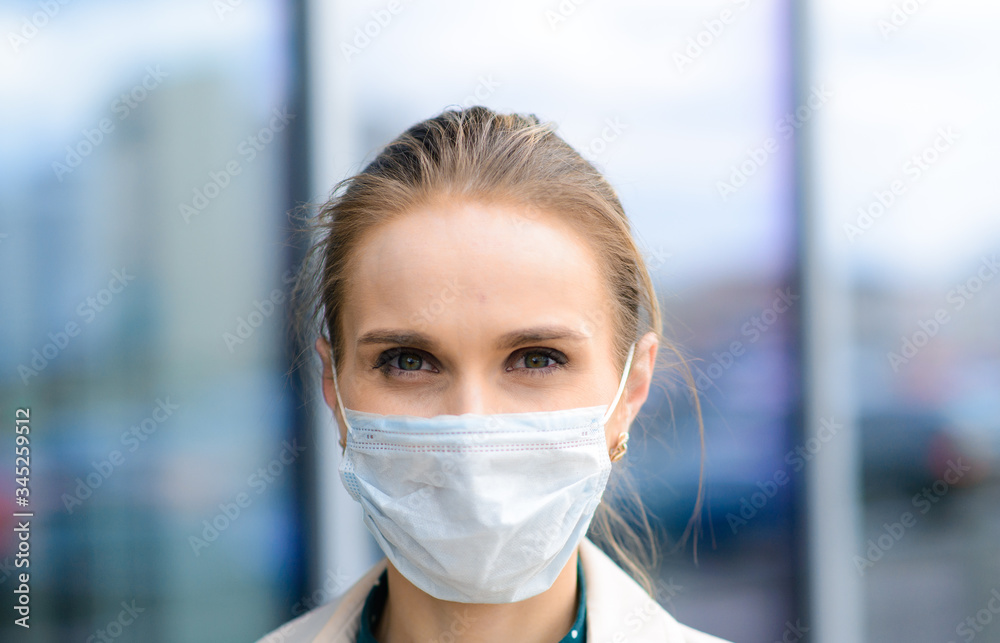 A young businesswoman wearing a health mask and talking on the phone in the city