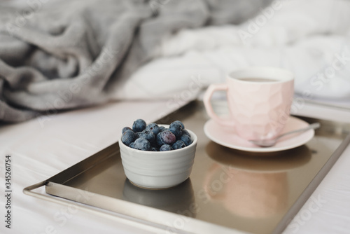 Cup of coffee and fresh blueberry served on a metal tray. Breakfast in bed. Morning coffee