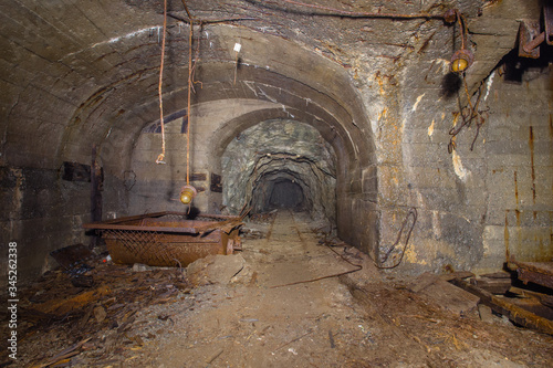 Underground abandoned iron ore mine tunnel with concrete timbering and rails