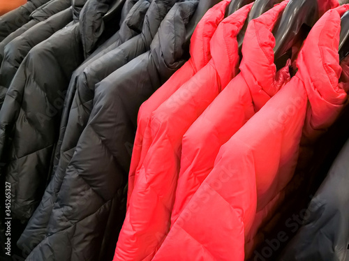 Multi colors of down jackets on the hangers at the store for sell. Collection of winter coats jackets hanged on a clothes rack.