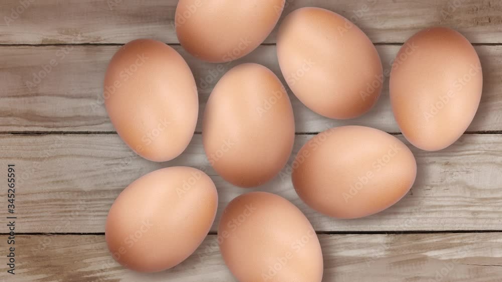 Chicken eggs move on a wooden table. Stop motion of eggs on brown wood background. Chicken eggs move on a wooden table. Stop motion of eggs on brown wood background.