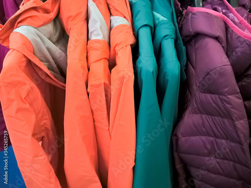 Multi colors of down jackets on the hangers at the store for sell. Collection of winter coats jackets hanged on a clothes rack.