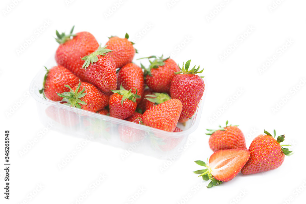 Fresh organic ripe strawberries in a plastic tray and two and a half near rotated isolated on white background Fresh organic ripe strawberries in a plastic tray and two and a half near rotated isolated on white background