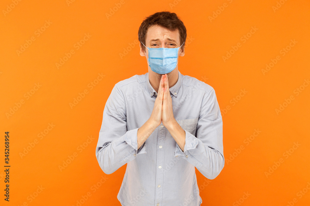 Please help me. Portrait of sad worry young worker man with medical mask standing with palm hands, worry and looking at camera begging or pleading. indoor studio shot isolated on orange background. Please help me. Portrait of sad worry young worker man with medical mask standing with palm hands, worry and looking at camera begging or pleading. indoor studio shot isolated on orange background.