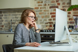 A woman in glasses works remotely on a desktop computer in her studio. A female boss is surprised by employees at a video conference at home. A female professor preparing for an online lecture.