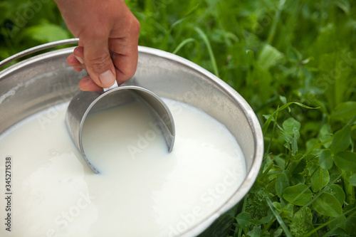 Scooping milk with metal mug.