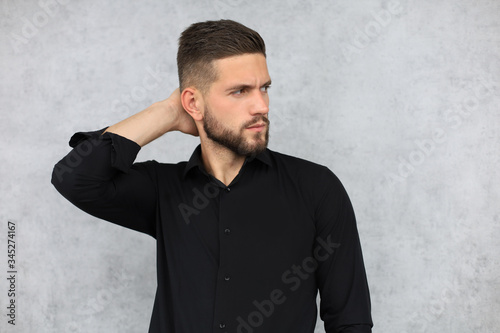 Thinking serious young handsome man is posing isolated over grey background