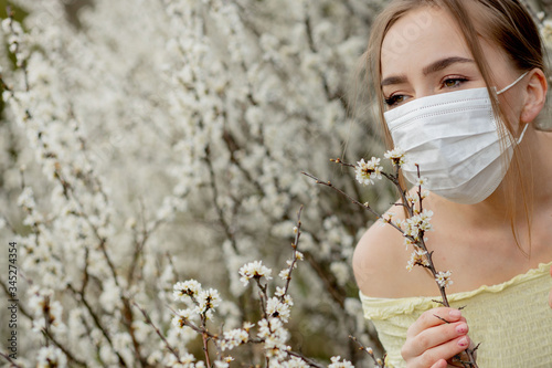 Young girl blowing nose and sneezing in tissue in front of blooming tree. Seasonal allergens affecting people. Beautiful lady has rhinitis