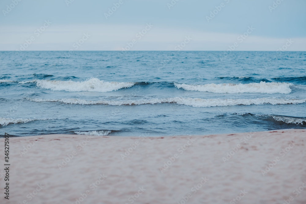 Sea coast with blue water. Stormy weather on the lake. Sandy beach with waves in bad weather. Nothern sea in wind.