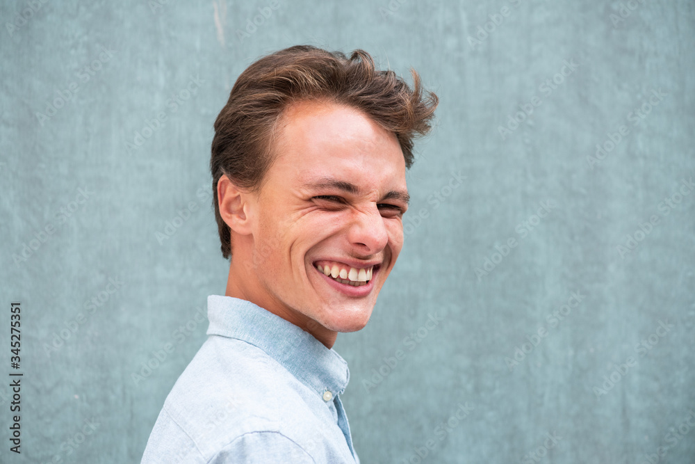 side portrait young man smiling by green wall