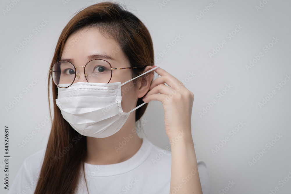 Asian Young woman in a white t-shirt and wear a medical mask that protects against the spread of coronavirus or COVID-19 disease. Studio Portrait with White Background. 