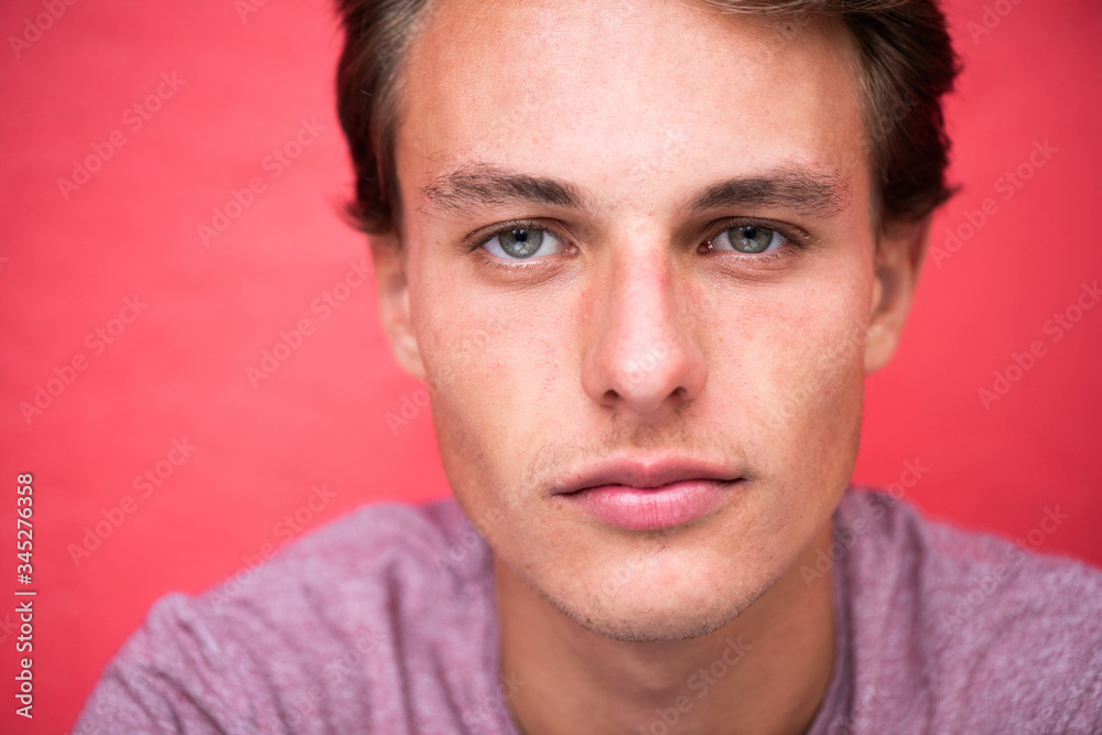 Close up handsome young man staring by red wall Close up handsome young man staring by red wall
