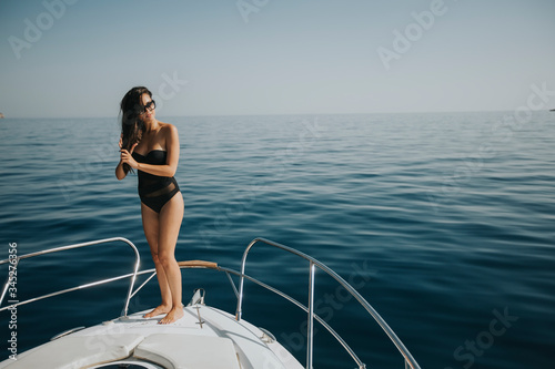 Young woman in swimwear standing on yacht front © BGStock72