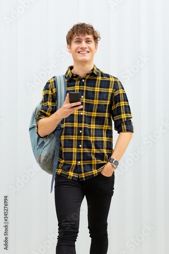 Foto happy young man with bag and cellphone by white background