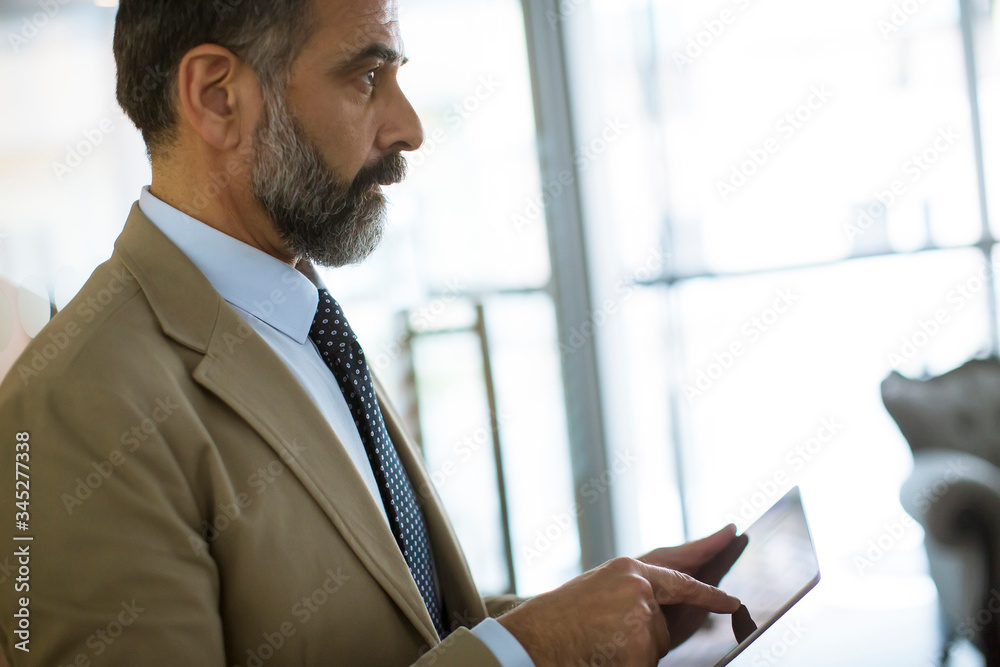 Fototapeta premium Elegant mature business man using multitasking multimedia digital tablet