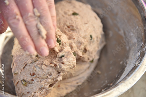 Close up of a baker kneading bread dough in a metal bowl. Handmade bread dough in a stainless steel bowl.