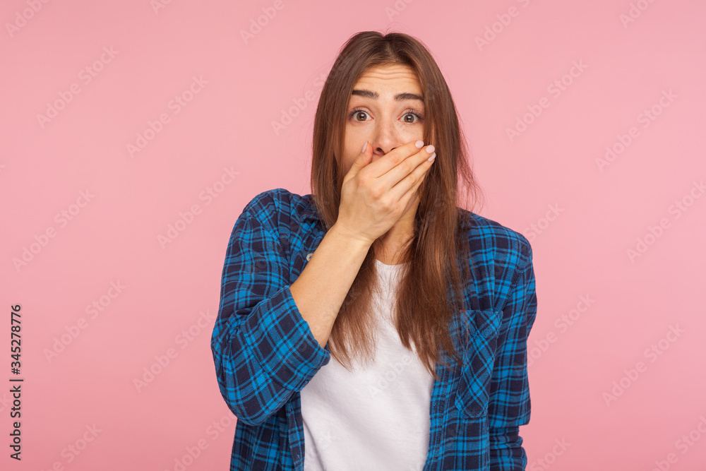 I won't tell anyone! Portrait of frightened scared girl in checkered shirt covering mouth with hand, keeping terrible truth secret, looking terrified. indoor studio shot isolated on pink background I won't tell anyone! Portrait of frightened scared girl in checkered shirt covering mouth with hand, keeping terrible truth secret, looking terrified. indoor studio shot isolated on pink background
