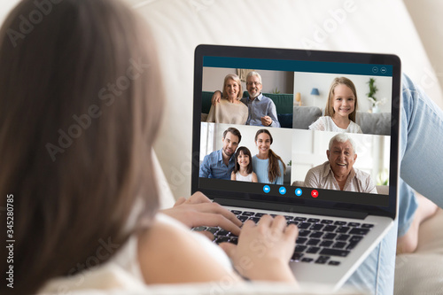 Young woman relax on couch at home talk on video call on laptop with relatives, millennial girl rest sit on sofa speak chat with family, have webcam conference, technology concept