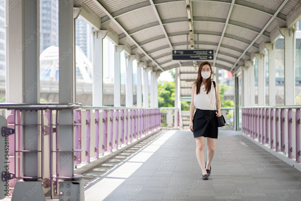 COVID-19 Pandemic Coronavirus Asian Woman in city street going to work. She wearing face mask protective for spreading of disease virus. 