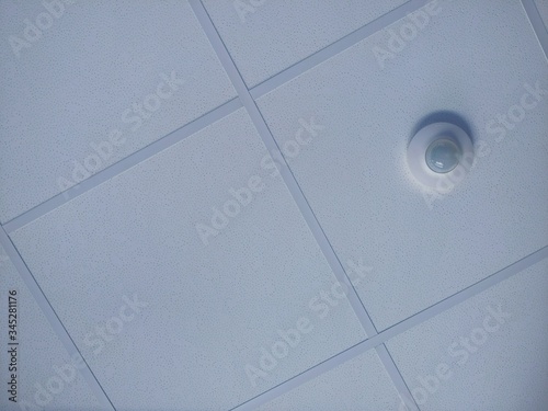 Textured tiles and motion sensor in the t-bar grid of a suspended ceiling