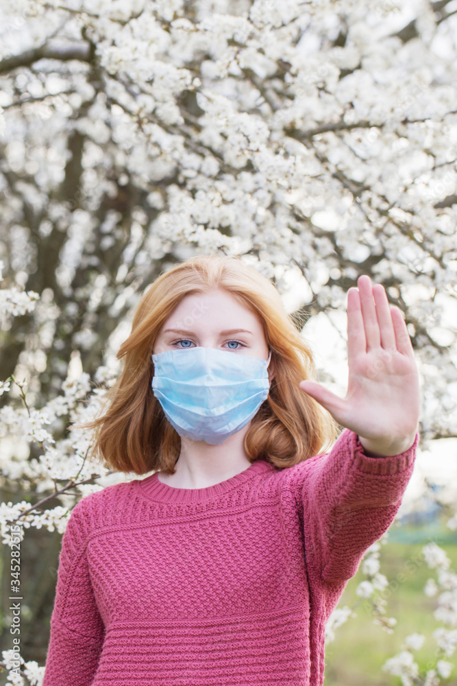teenager girl in medical mask in spring flowering garden. Concept of social distance and prevention of coronavirus. teenager girl in medical mask in spring flowering garden. Concept of social distance and prevention of coronavirus.