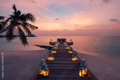 Romantic dinner on the beach with sunset, candles with palm leaves and sunset sky and sea. Amazing view, honeymoon or anniversary dinner landscape. Exotic island evening horizon, romance for a couple  photo