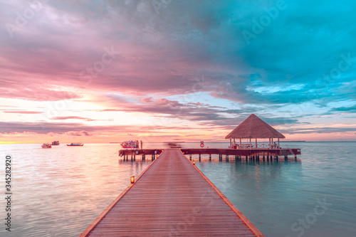 Amazing sunset landscape. Picturesque summer sunset in Maldives. Luxury resort villas seascape with soft led lights under colorful sky. Dream sunset over tropical sea  fantastic nature scenery 