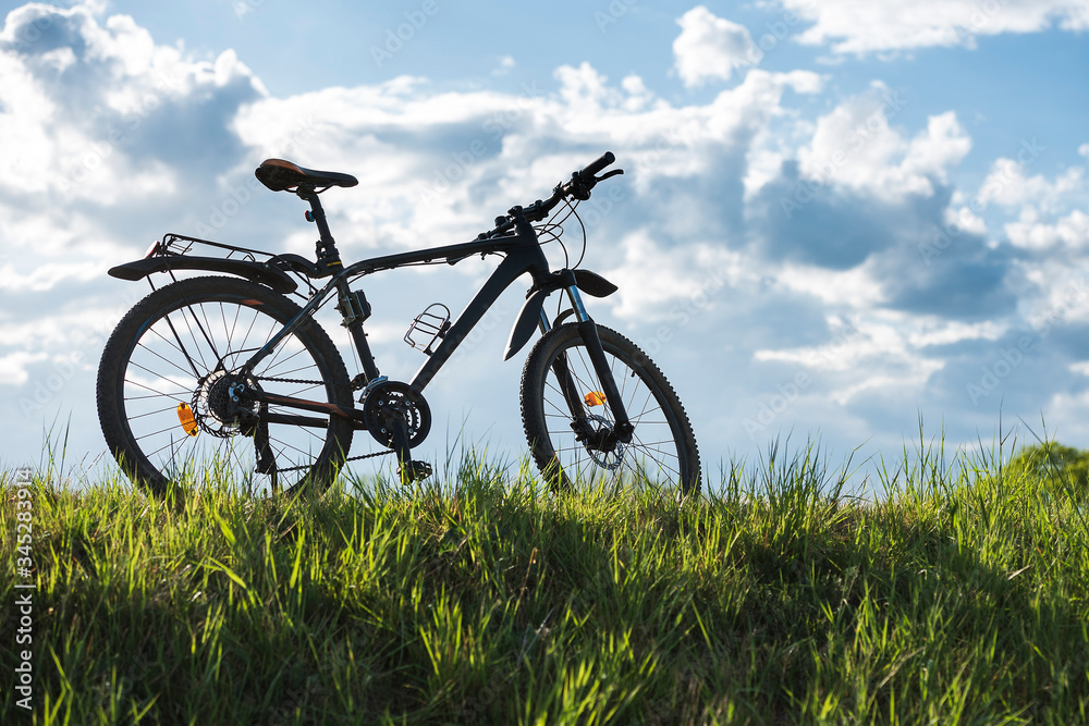 Mountain bike stands on the grass with blue sky in the background Mountain bike stands on the grass with blue sky in the background