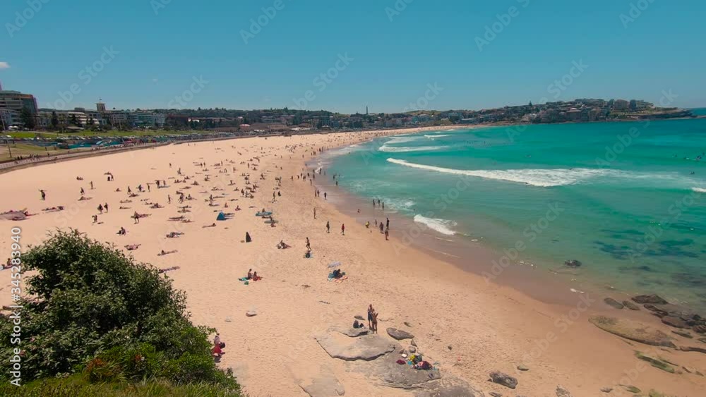 Bondi Beach Sydney holiday scene. Famous vacation spot in city, with beautiful ocean, sun, sea and sand. Tourists sunbathing on beach, with waves washing in. Australia. 4k. Bondi Beach Sydney holiday scene. Famous vacation spot in city, with beautiful ocean, sun, sea and sand. Tourists sunbathing on beach, with waves washing in. Australia. 4k.