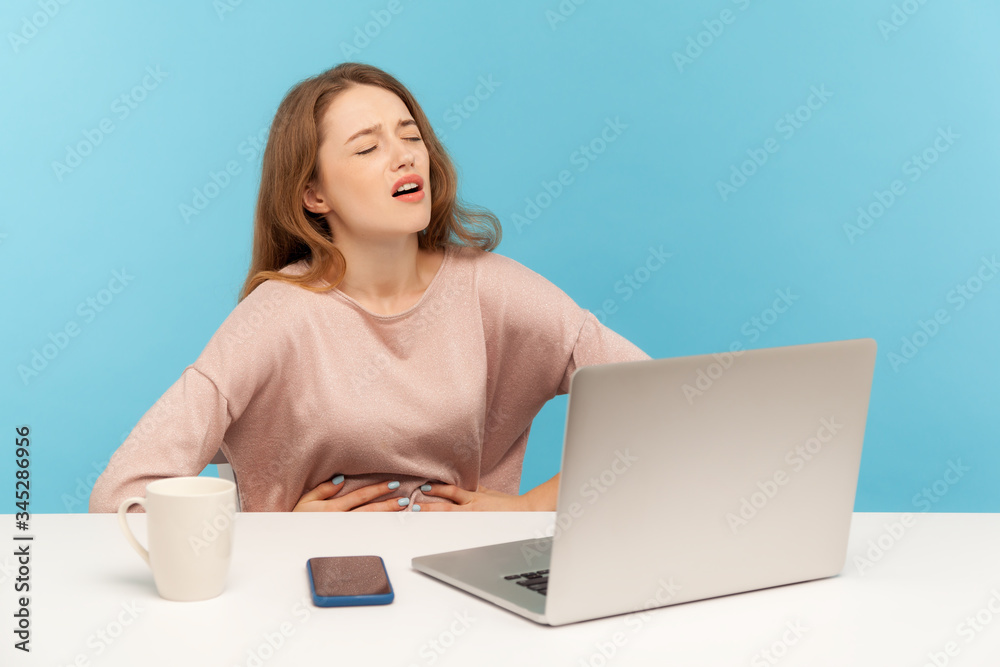 Periods cramps, stomachache at workplace. Woman employee holding painful belly feeling discomfort, suffering heartburn, gastrointestinal disorder. indoor studio shot isolated on blue background Periods cramps, stomachache at workplace. Woman employee holding painful belly feeling discomfort, suffering heartburn, gastrointestinal disorder. indoor studio shot isolated on blue background
