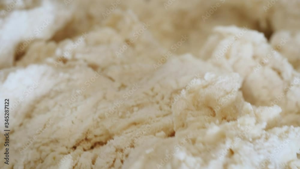 Stirring flour, water and yeast into bread dough with a wooden spoon. A home baker stirs raw sourdough starter forming gluten. Baking bread is the current food trend despite flour and yeast shortages. Stirring flour, water and yeast into bread dough with a wooden spoon. A home baker stirs raw sourdough starter forming gluten. Baking bread is the current food trend despite flour and yeast shortages.