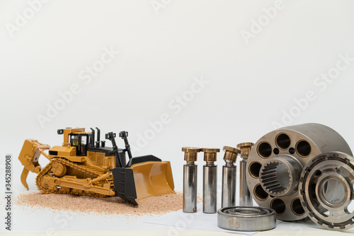 hydraulic piston pump parts with bulldozer tractor model on white background, repair maintenance heavy machinery concept