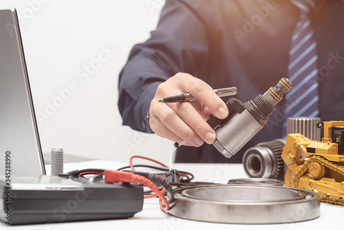 Professional engineer reaching hand to solenoid valve for during working day in office, repair maintenance heavy machinery concept